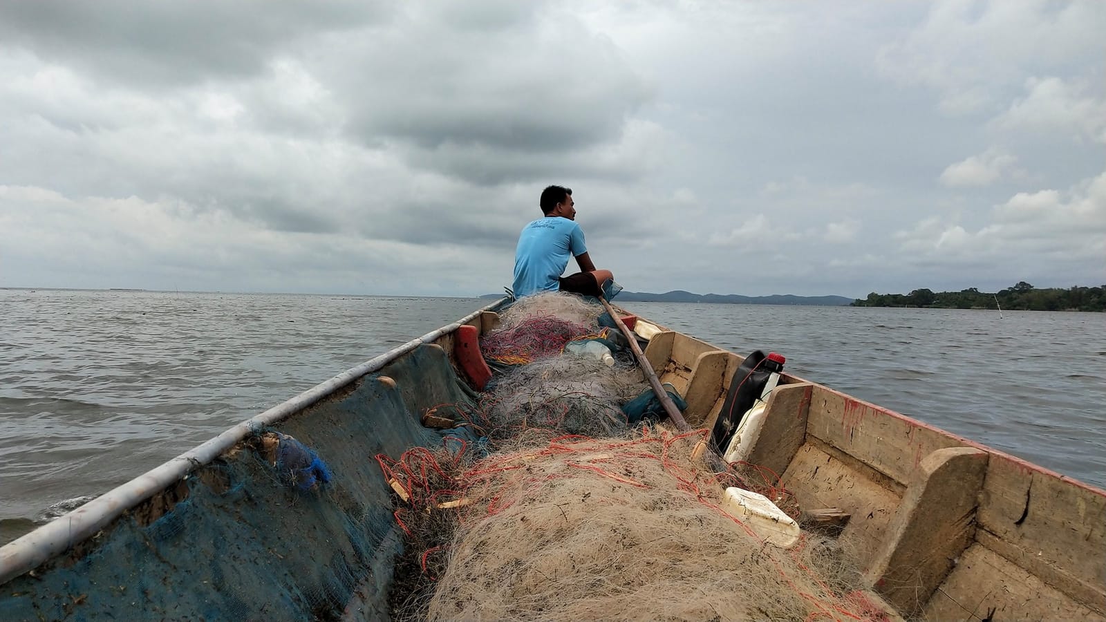 ชาวประมงนั่งบนเรือพร้อมอวน กลางทะเลสาบ